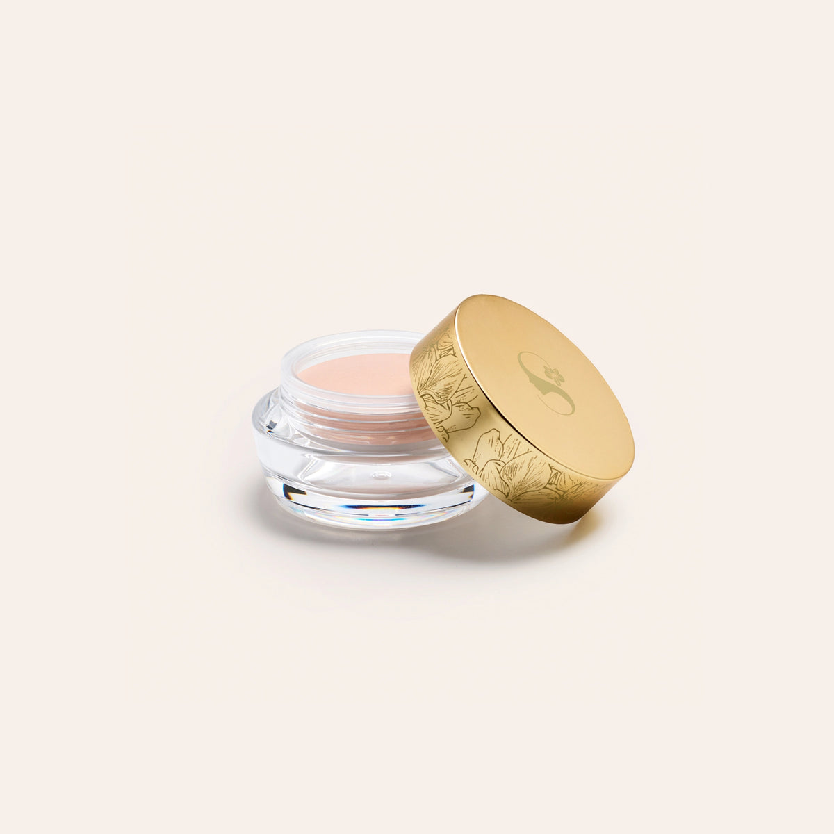 EyeLuminator™ Under Eye Brightening Cream by SeneGence: An open clear jar of peach cream beside an orchid-engraved gold lid.